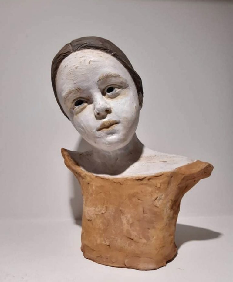 A terracotta bust of a ballerina with a neutral-colored dress and a contemplative expression.